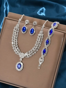 Macro shot of silver jewelry set with blue oval sapphires and diamonds on blue silk