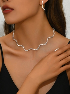 Detailansicht von elegantem Silberwellen-Halsketten- und Ohrringset an einem Brautmodel