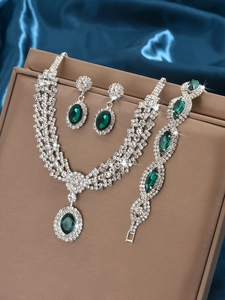 Detailed view of luxury silver-tone jewelry set with deep green oval gemstones on a leather box