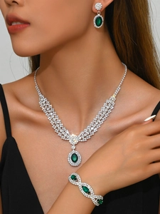 Close-up of luxury jewelry set featuring deep green emerald-style oval gemstones