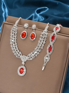 Detailed close-up of luxury silver jewelry set with red gemstones on dark blue silk