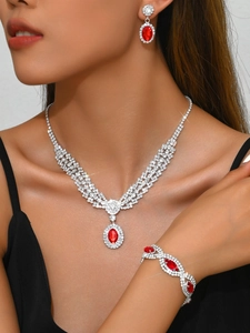 Detail of luxury silver-tone jewelry set featuring sparkling red oval gemstones and white crystals