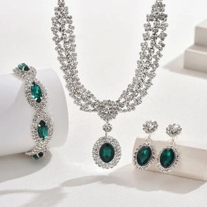Luxurious silver jewelry set featuring emerald green gemstones and micro-paved rhinestones