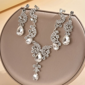 Elegant bridal jewelry set with pear-cut crystals on champagne satin display base