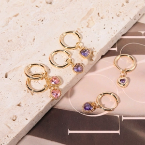 Detail of heart-shaped birthstone charms on gold hoop earrings with beaded metal edges