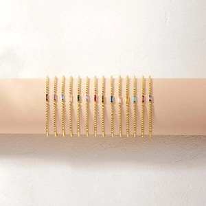 Detailed macro view of gold ball chain bracelets with colorful baguette-cut birthstones