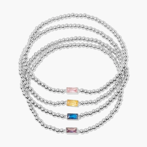 Close-up of four minimalist beaded bracelets with rectangular crystals in multiple colors
