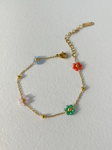 Detalle de flores de cuentas de colores en una delicada pulsera de cadena dorada