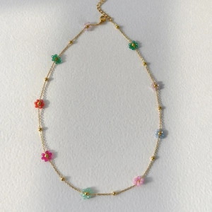 Vista detallada del collar de flores de colores con cadena dorada y cierre de mosquetón