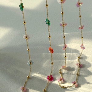 Collares de flores coloridas en acabado dorado con cuentas vibrantes de color rosa