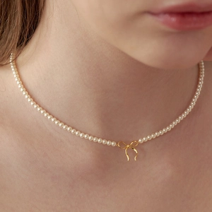 Collier élégant en perles faites main avec pendentif nœud doré sur un choker délicat