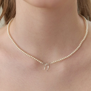 Gros plan d'un collier de perles fait main avec pendentif nœud plaqué or sur le cou