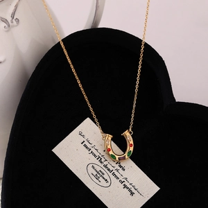Collar de herradura dorado con circonitas de colores en soporte de terciopelo negro