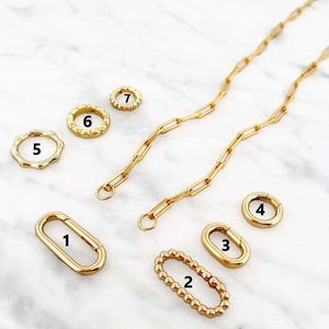 Selection of gold-plated 18K DIY jewelry connectors and clasps on marble surface