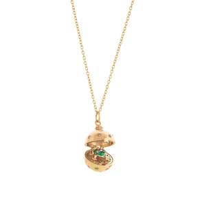 Detalle de medallón dorado que muestra una rana de esmalte verde con gemas finas