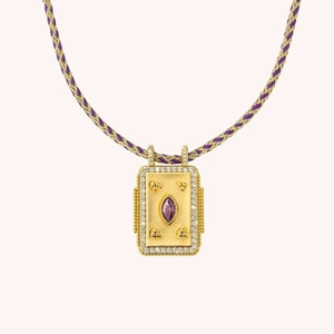 Macro view of rectangular gold pendant necklace with marquise purple gemstone and woven cord