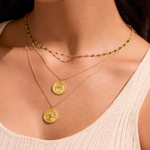 Detail van gelaagde gouden kettingen met Hamsa-hand en levensboom hangers voor vrouwen