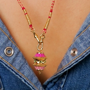 Detalle de un colgante bañado en oro de 18K con esmalte rosa sobre fondo denim azul