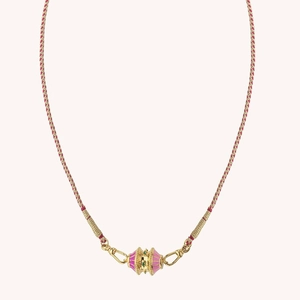 Detalle de un collar trenzado bañado en oro de 18K con esmalte rosa y detalles de gemas verdes