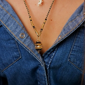 Detalle del colgante de linterna bañado en oro 18K con esmalte negro y circonitas en cordón
