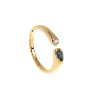 Détail d'une bague dorée avec une pierre de naissance ronde et une pierre bleue en poire