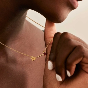 Detail of Cupid arrow pendant with red heart gemstone on gold stainless steel chain