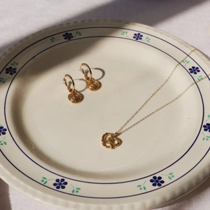 Détail d'un ensemble de bijoux dorés 18 carats sur une assiette vintage en porcelaine fleurie