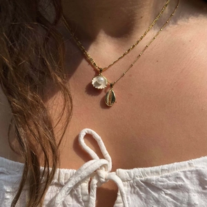 Detail of gold shell and mermaid pearl necklaces worn on sun-kissed skin