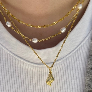 Close-up of a three-layer gold-plated necklace with sea shell pendant and white pearls