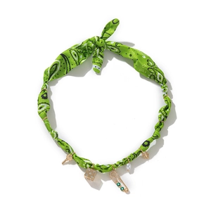 Detail of green paisley fabric necklace with golden key, pearl and evil eye charms