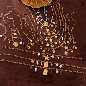 Détails de breloques dorées avec fleurs en émail coloré, coquillages et perles sur colliers