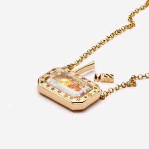 Détail macro du médaillon vintage en or 18k avec pierres étoilées et breloque MISS