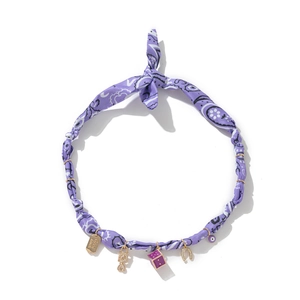 Detailed shot of purple bandana fabric necklace with golden Good Luck and evil eye charms