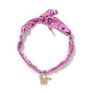Detail of pink paisley fabric choker with a gold padlock charm and crystal key pendant