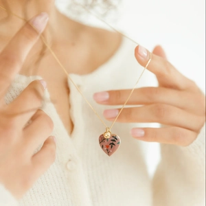 Détail du collier médaillon cœur en or 18 carats avec émail floral rose sur modèle