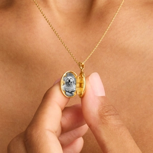 Detail of opening oval gold locket necklace with custom black and white dog photo