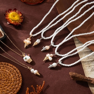 Detailed flat lay of dessert-inspired pearl necklaces with gold chains and colorful gems