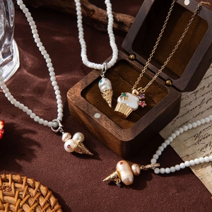 Detail of pearl chain necklace featuring ice cream and cupcake pendants with gems