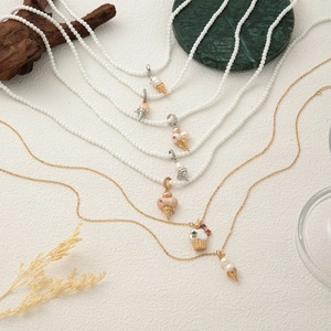 Detailed view of colorful pearl ice cream cone and cupcake charms on gold necklaces