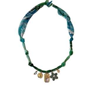 Detail of bohemian necklace with leopard cord, blue flower, sun charm and star charms