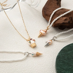 Detailed view of pearl necklaces with ice cream and cupcake shaped gemstone pendants