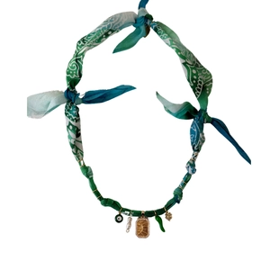 Detail of bohemian fabric necklace with evil eye, pearl and sun engraved pendants