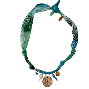 Detail of bohemian fabric chain necklace with gold sun charms and pearl pendants