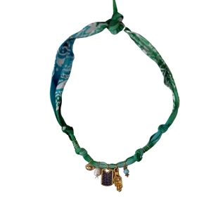 Detail of bohemian fabric necklace with evil eye, pearl, and Hamsa hand charms