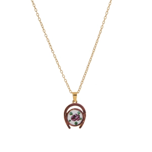 Close-up of vintage golden necklace with horseshoe pendant and painted floral ceramic charm
