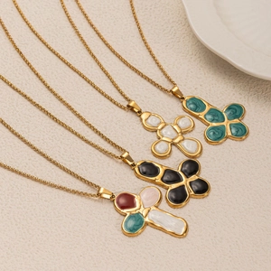 Macro view of four colorful enamel cross pendants with gold plating on titanium steel chains