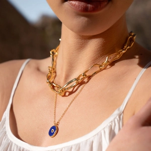 Detail of layered 18k gold plated stainless steel necklace with blue evil eye pendant on model