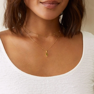 Detail of layered 18K gold plated necklaces featuring green zircon and crescent charms