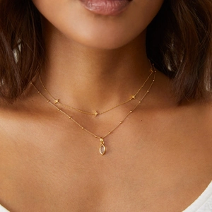 Close-up of double-layered gold necklace with star charms and marquise zircon pendant