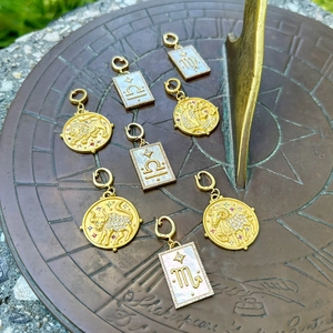 Macro detail of zodiac pendants with pearl shell on vintage bronze sundial background